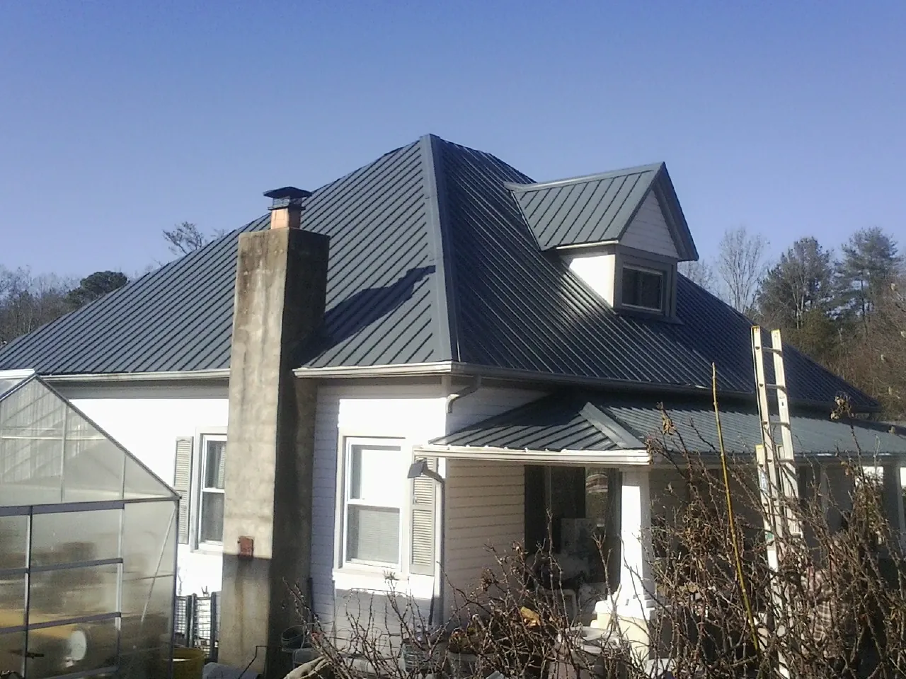 Dark blue standing seam metal roof on a white farmhouse with dormer — Slate & Tile Roof Repair by Roofing Brothers in Bombay