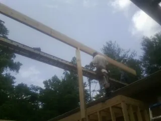 Carpenter setting a ridge beam over a new addition frame — Ice Dam Removal by Roofing Brothers in Bombay