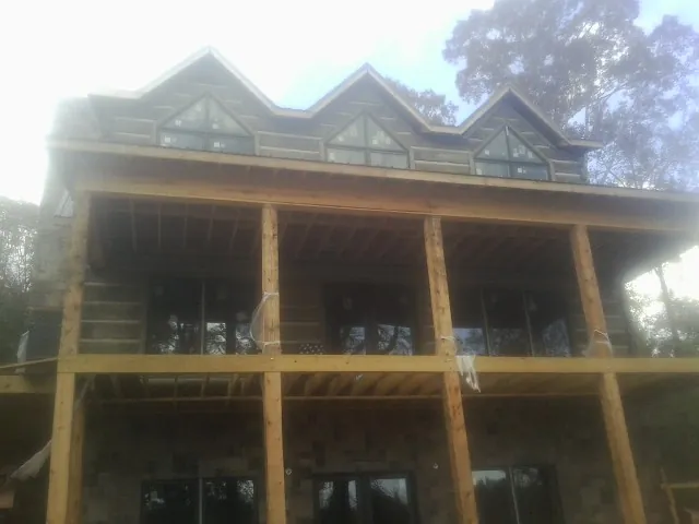 Dormers and porch framing on a large log home under construction — Roof Coating work by our crew in Bombay