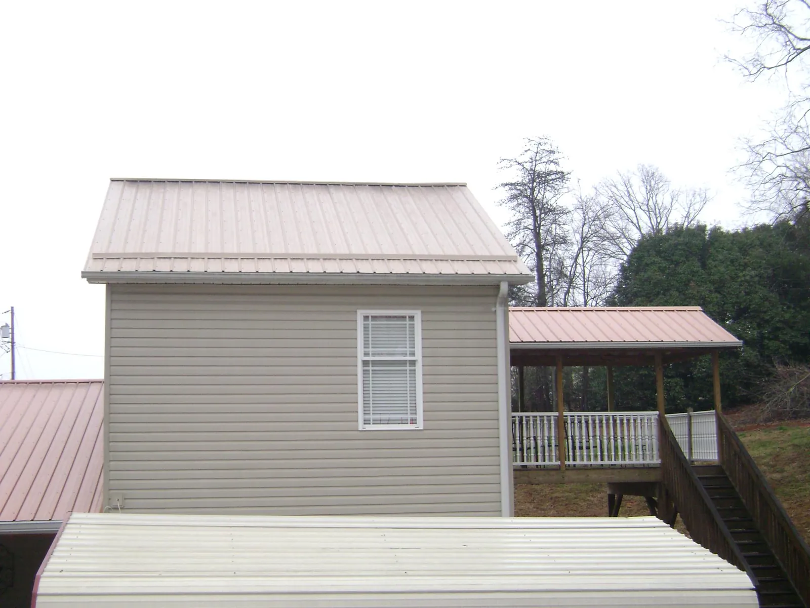 Tan metal roofs on a two story addition and attached porch, from a Roof Replacement job in Bombay
