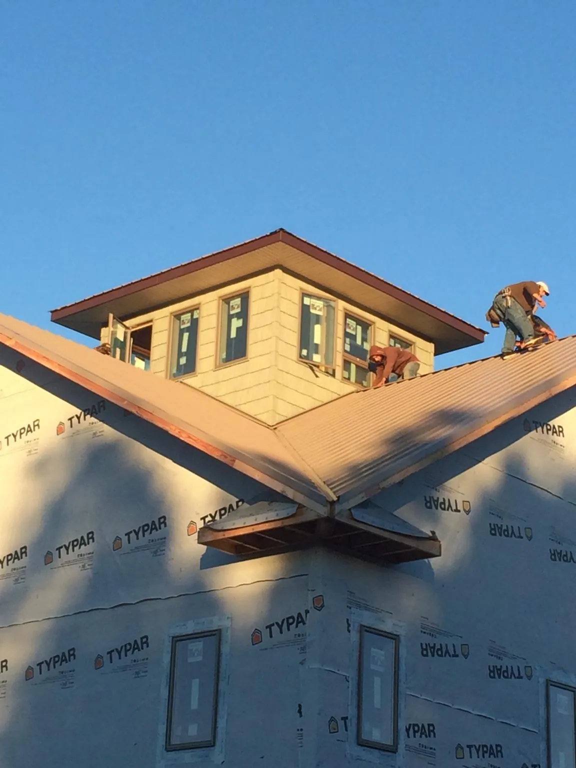 Roofers working around a rooftop cupola on a new metal roof at sunset — Roof Waterproofing in Bombay by Roofing Brothers